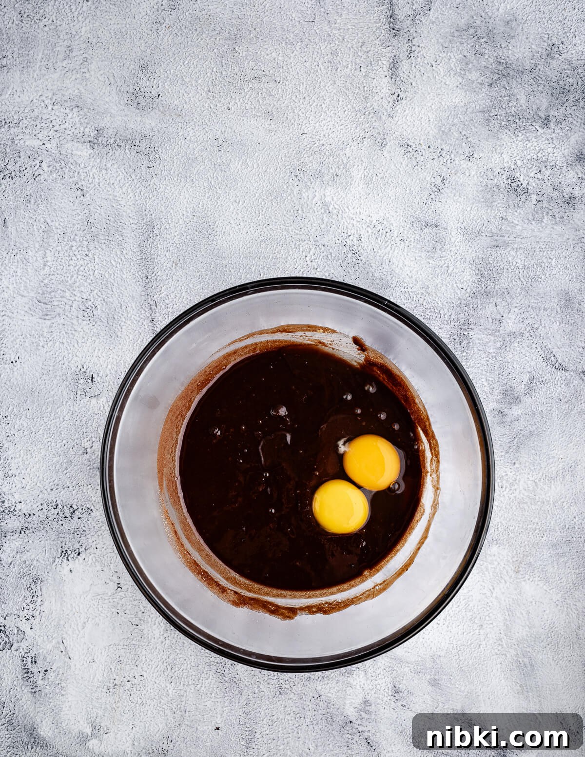 a bowl of melted chocolate and sugar with eggs on top.
