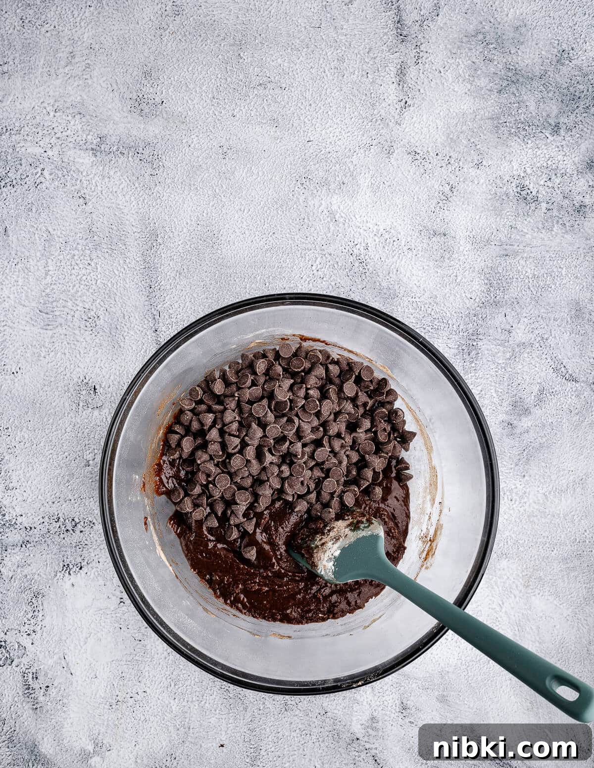 a bowl of chocolate cookie dough with chocolate chips on top.