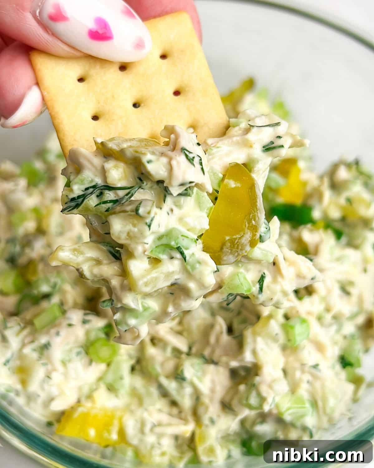 chicken salad in a bowl and on a cracker in hand