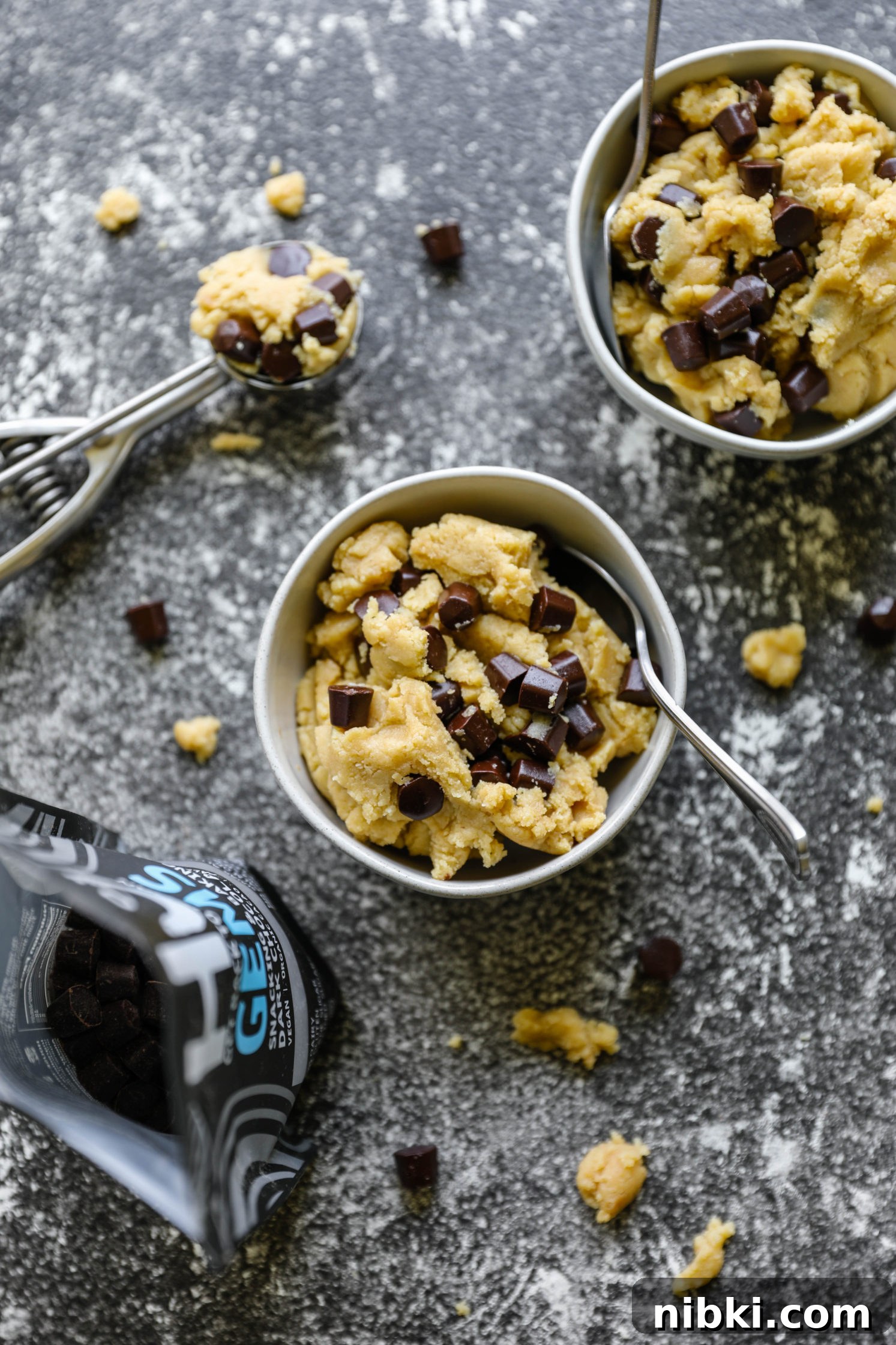 No-Bake Edible Vegan Cookie Dough Recipe 5 Edible Vegan Cookie Dough served in bowls with a spoons with a cookie scoop and a bowl of chocolate Gems