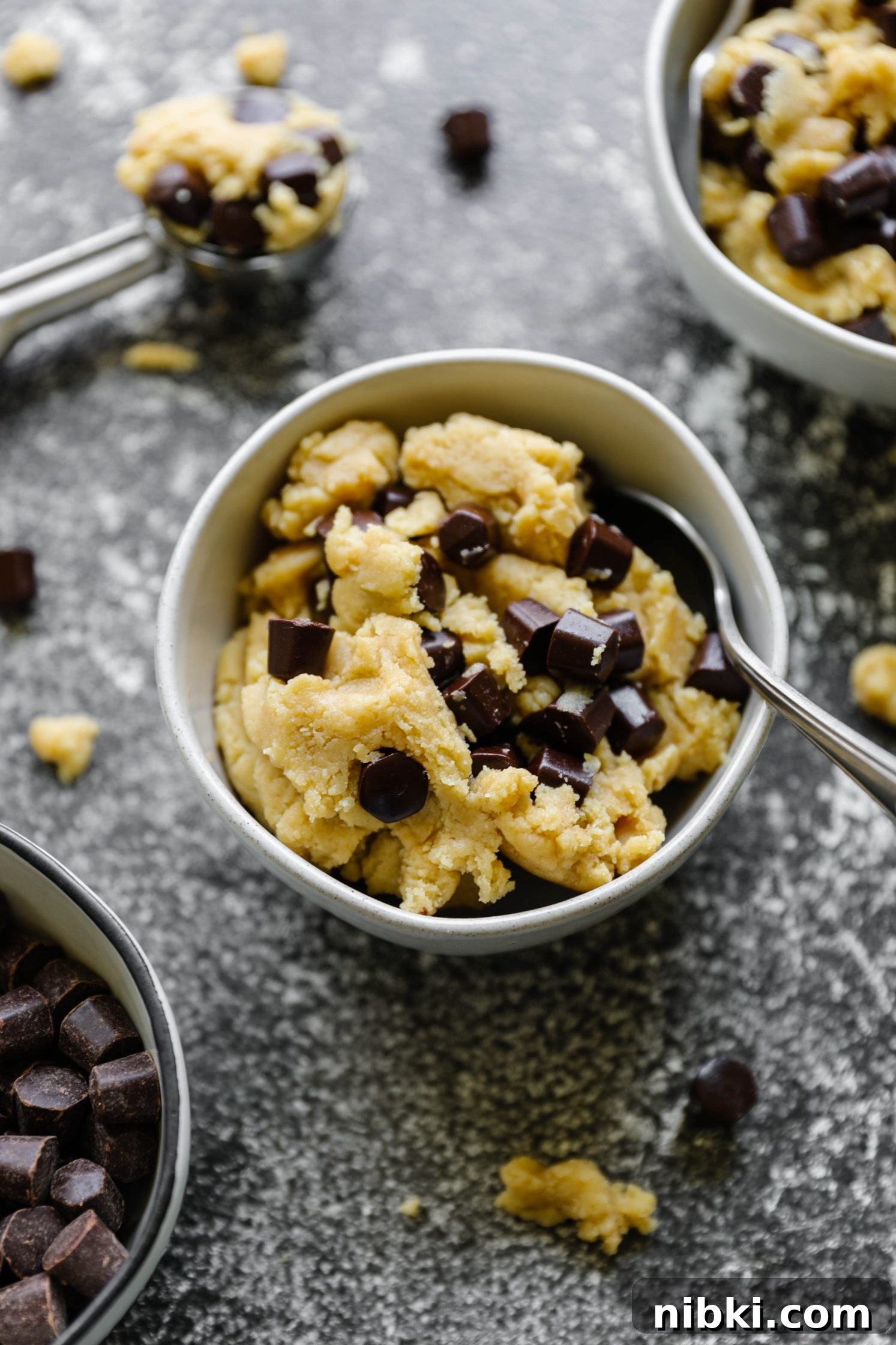 No-Bake Edible Vegan Cookie Dough Recipe 7 Edible Vegan Cookie Dough served in bowls with a cookie scoop and a bowl of chocolate Gems