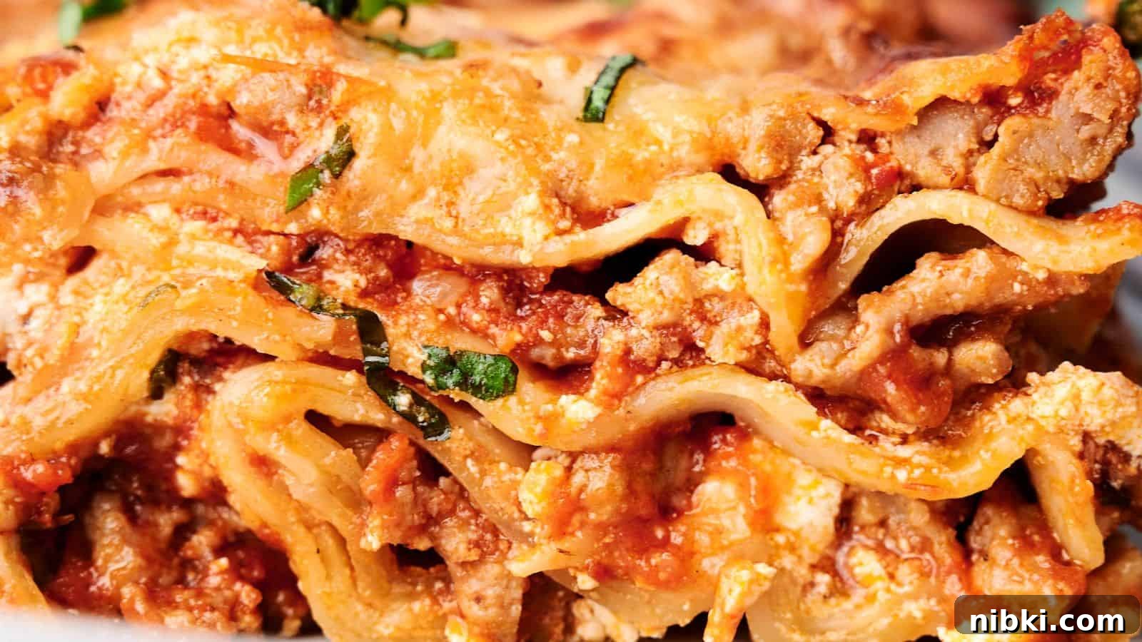 33 Christmas Potluck Recipes to Bring December Magic 10 Close-up of a delicious slice of lasagna, showcasing layers of pasta, ground meat, tomato sauce, ricotta cheese, and garnished with chopped basil.