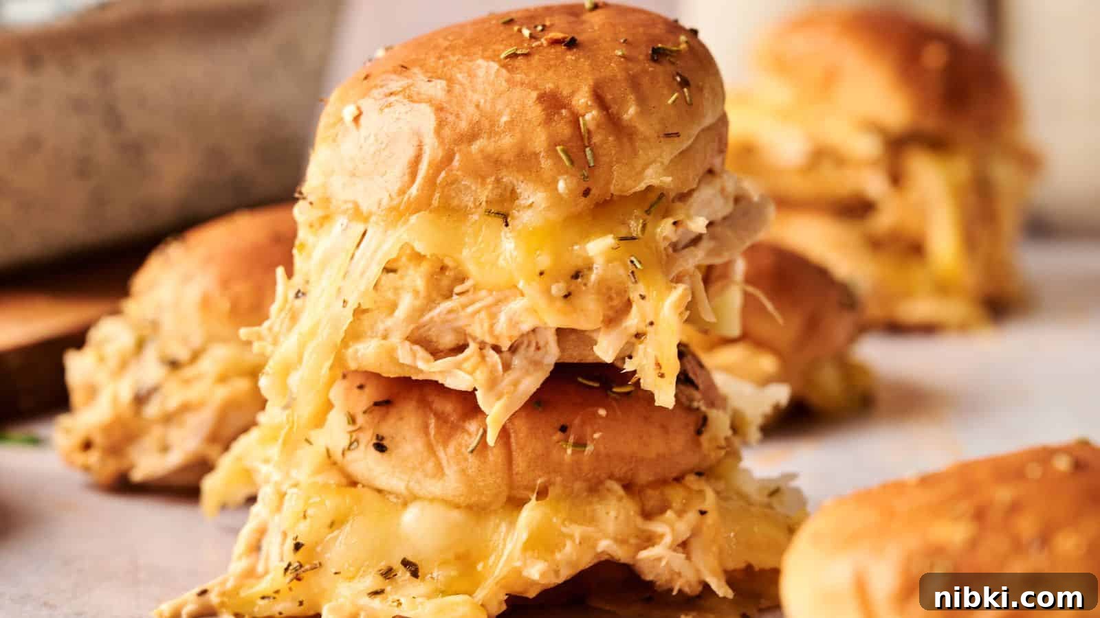 33 Christmas Potluck Recipes to Bring December Magic 27 A stack of slider sandwiches filled with shredded chicken and melted cheese, topped with herbs, on a light surface.
