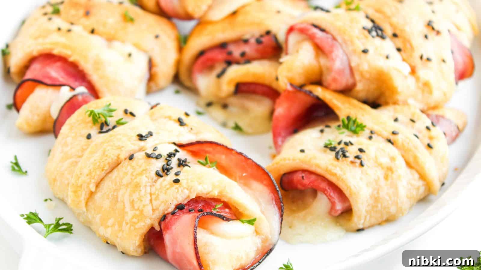 33 Christmas Potluck Recipes to Bring December Magic 28 A plate of baked crescent rolls filled with slices of ham and melted cheese, topped with black sesame seeds and garnished with parsley.