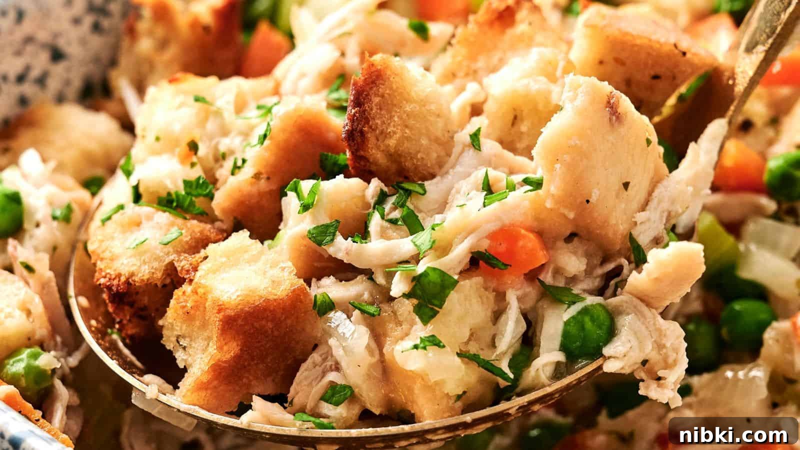 33 Christmas Potluck Recipes to Bring December Magic 29 A close-up of a spoonful of chicken stuffing, showcasing croutons, shredded chicken, peas, carrots, and sprinkled herbs.