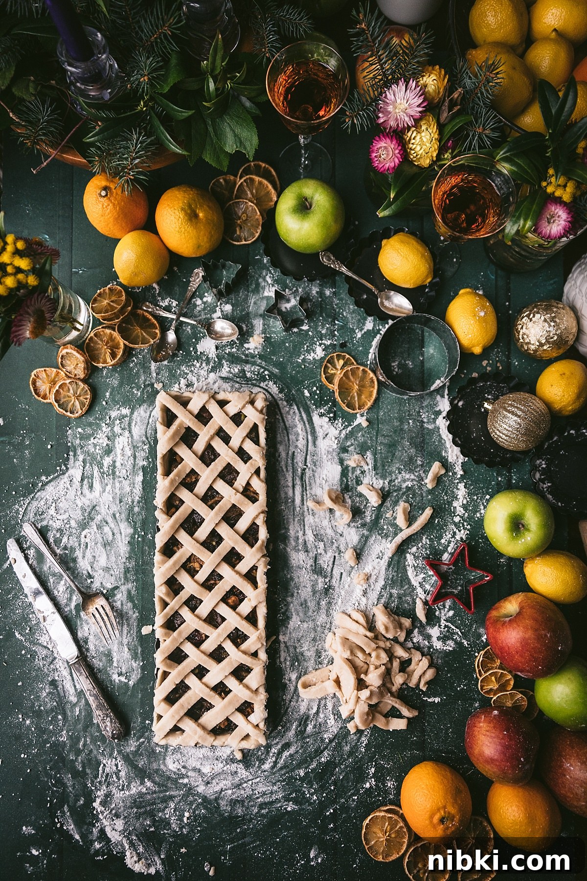 pre-baked christmas tart with lattice top filled with mincemeat filling. luxurious shot surrounded with festive holiday elements