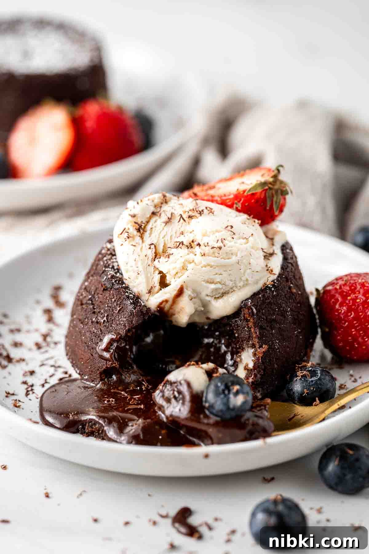 Dairy free lava cake with ice cream and berries on a white plate.