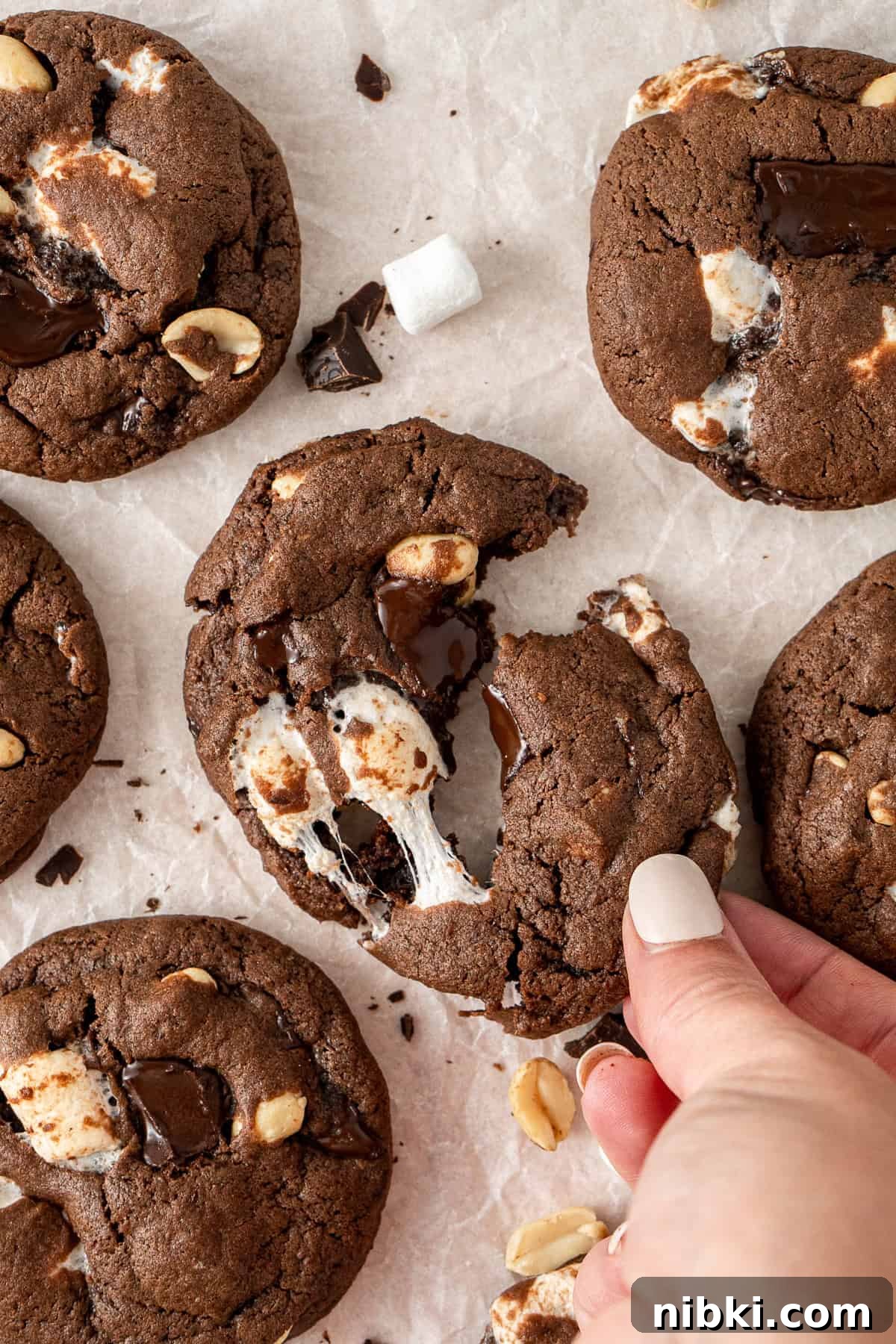 A hand breaking apart a rocky road cookie.