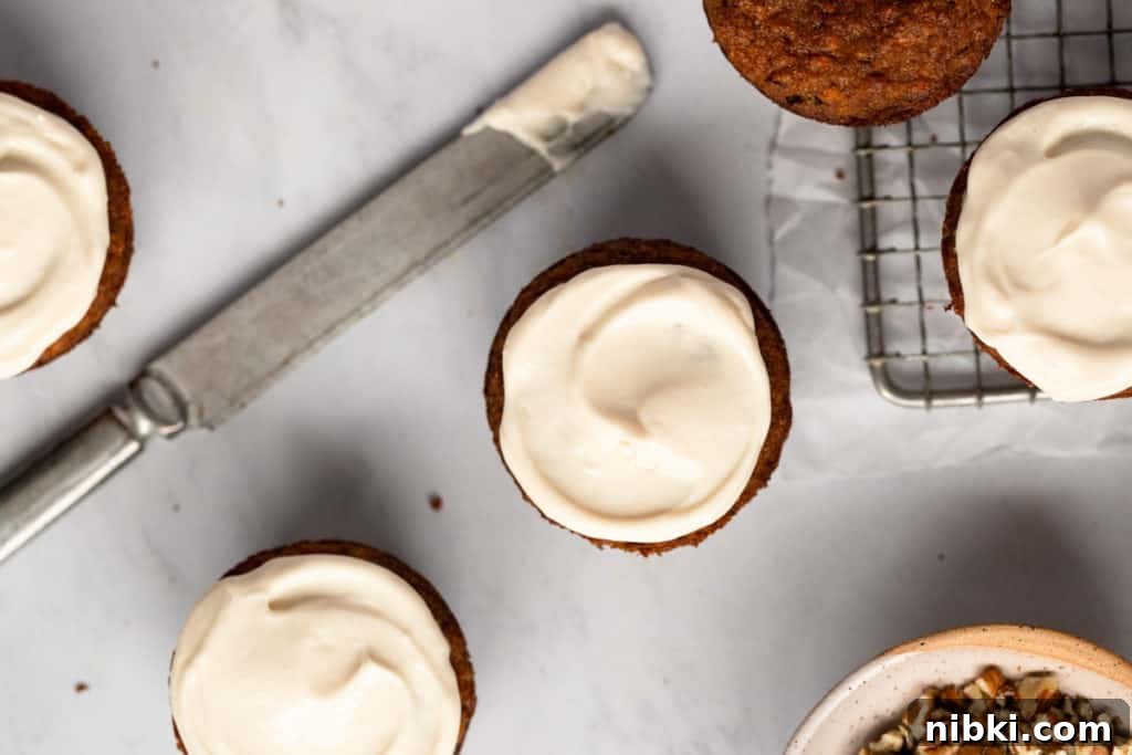 Maple cream cheese frosting on muffins with a knife alongside.
