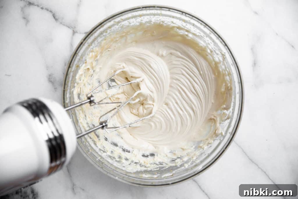 Beaters mixing the maple cream cheese frosting in a bowl.