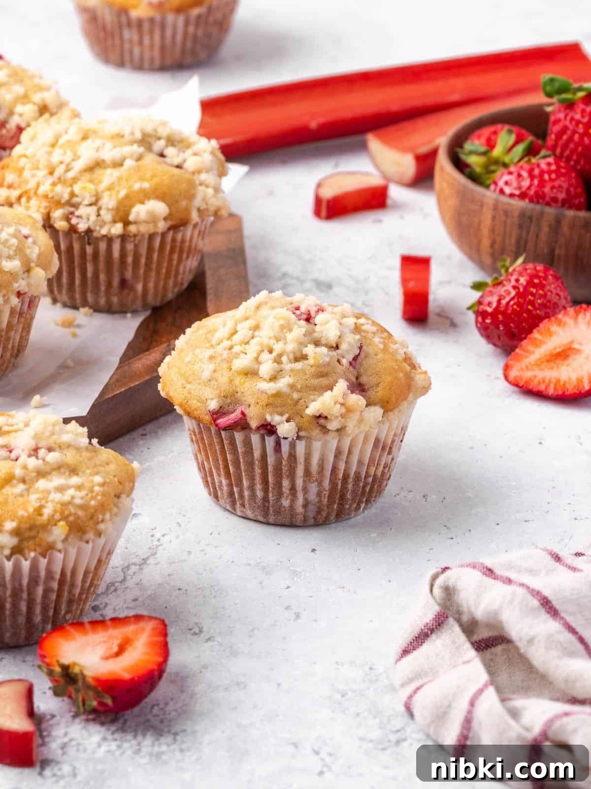Strawberry Rhubarb Muffins with Lemony Streusel Topping 2 Strawberry rhubarb muffins with lemon streusel topping on a wooden board.