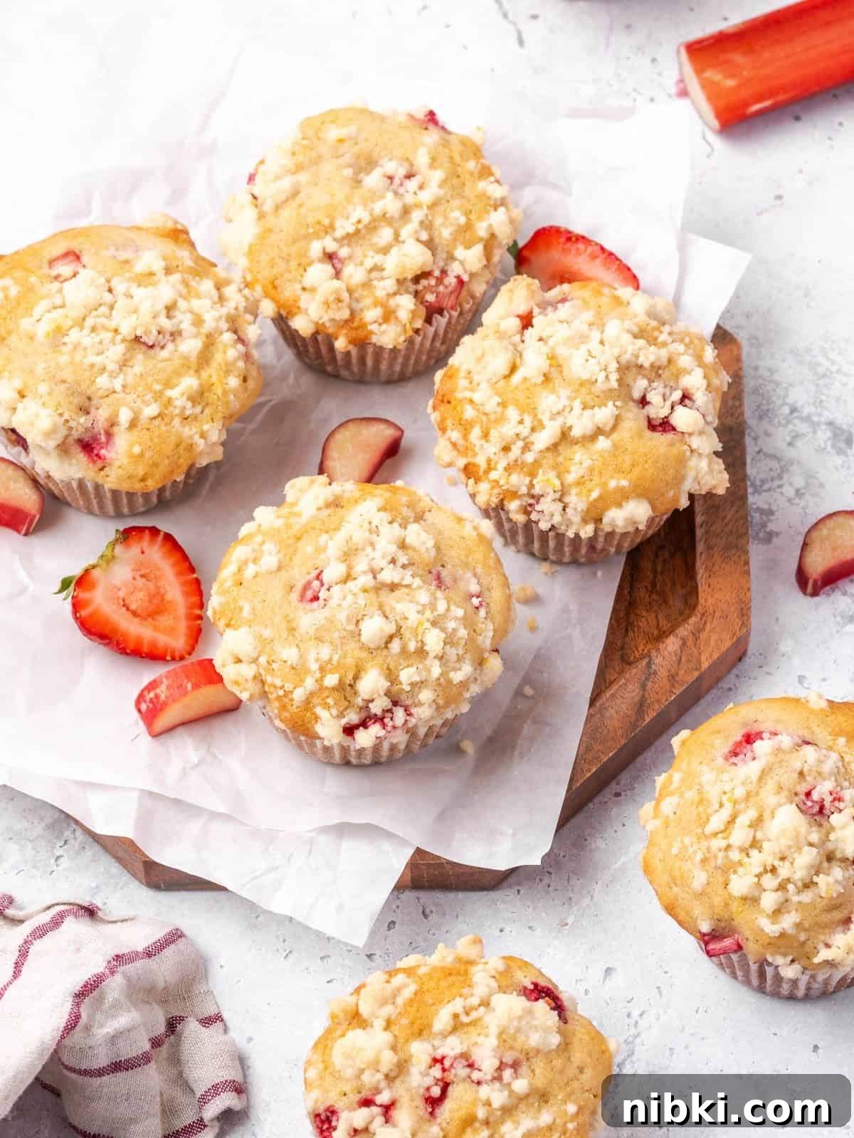 Strawberry Rhubarb Muffins with Lemony Streusel Topping 10 Strawberry rhubarb muffins with lemon streusel topping on a wooden board.