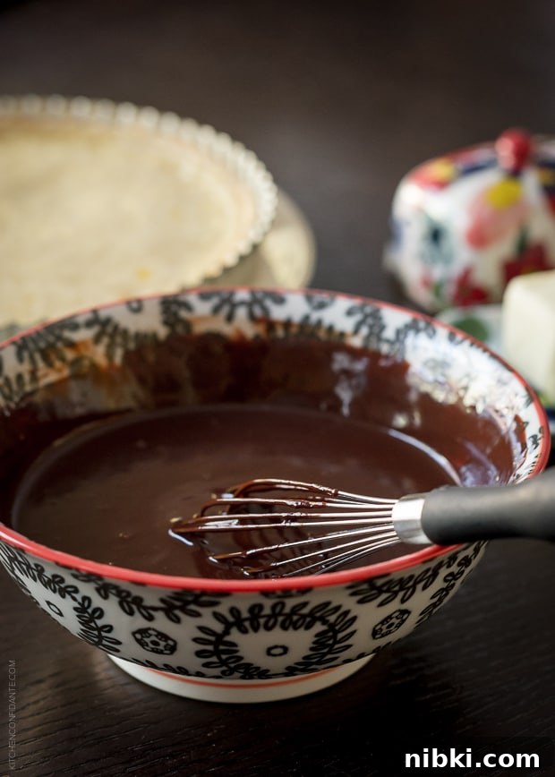 Coconut Custard Tart with Chocolate Ganache Recipe 3 A bowl of chocolate ganache with a whisk.