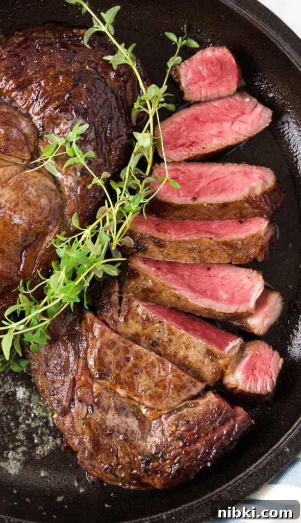 Garlic Herb Ribeye Steak Marinade for Grilling 10 Close up of sliced ribeye steak in a skillet with fresh thyme