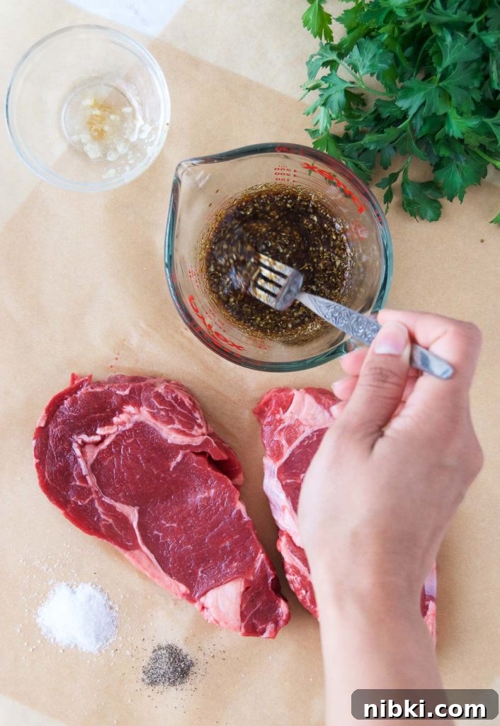 Garlic Herb Ribeye Steak Marinade for Grilling 2 A woman stirs a steak marinade with a fork next to steaks