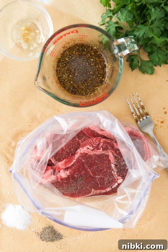 Garlic Herb Ribeye Steak Marinade for Grilling 5 Steaks in a gallon-sized plastic bag next to marinade