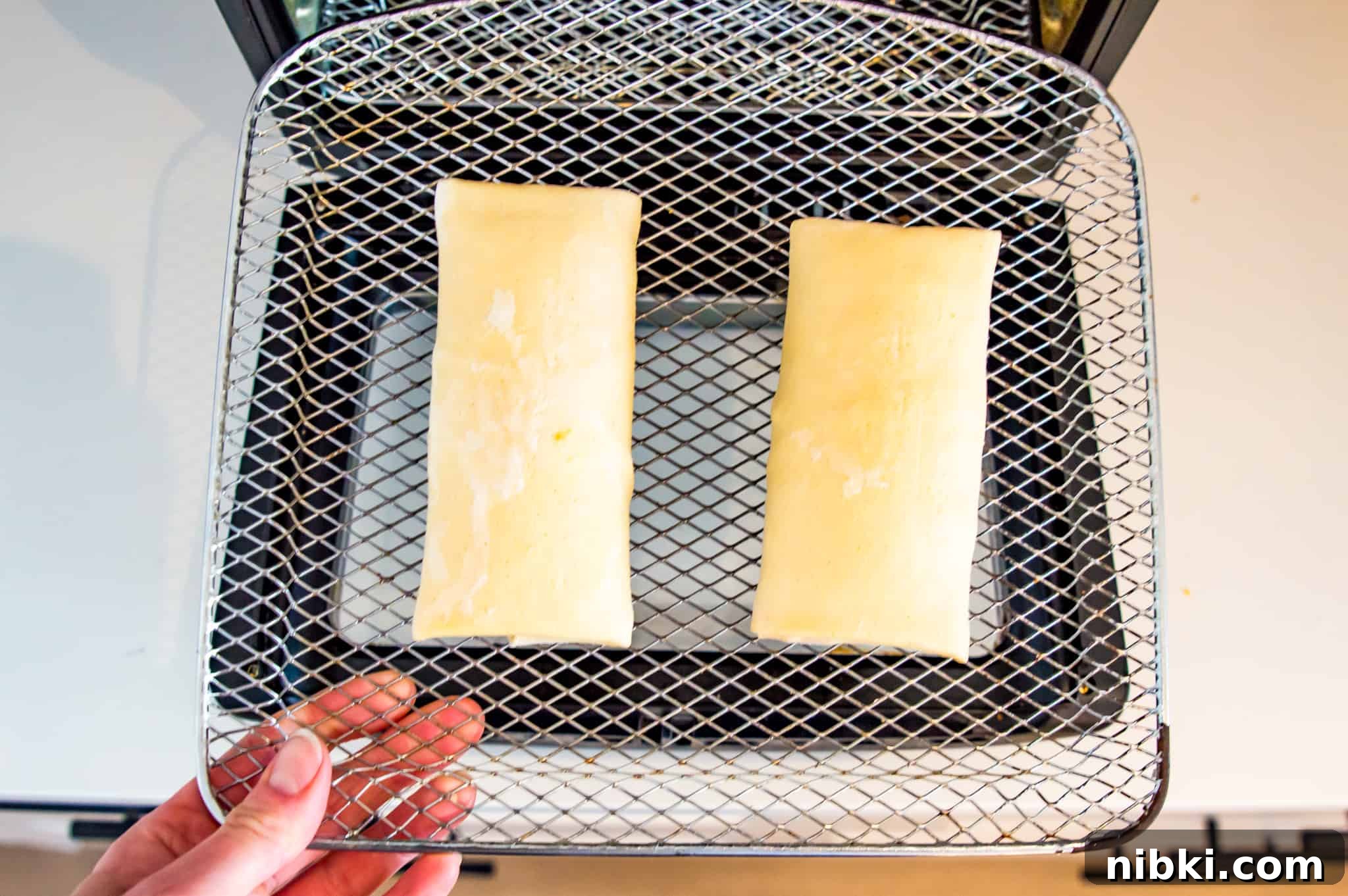 How to Air Fry a Frozen Burrito for Crispy Results 3 Two frozen burritos on an air fryer tray.