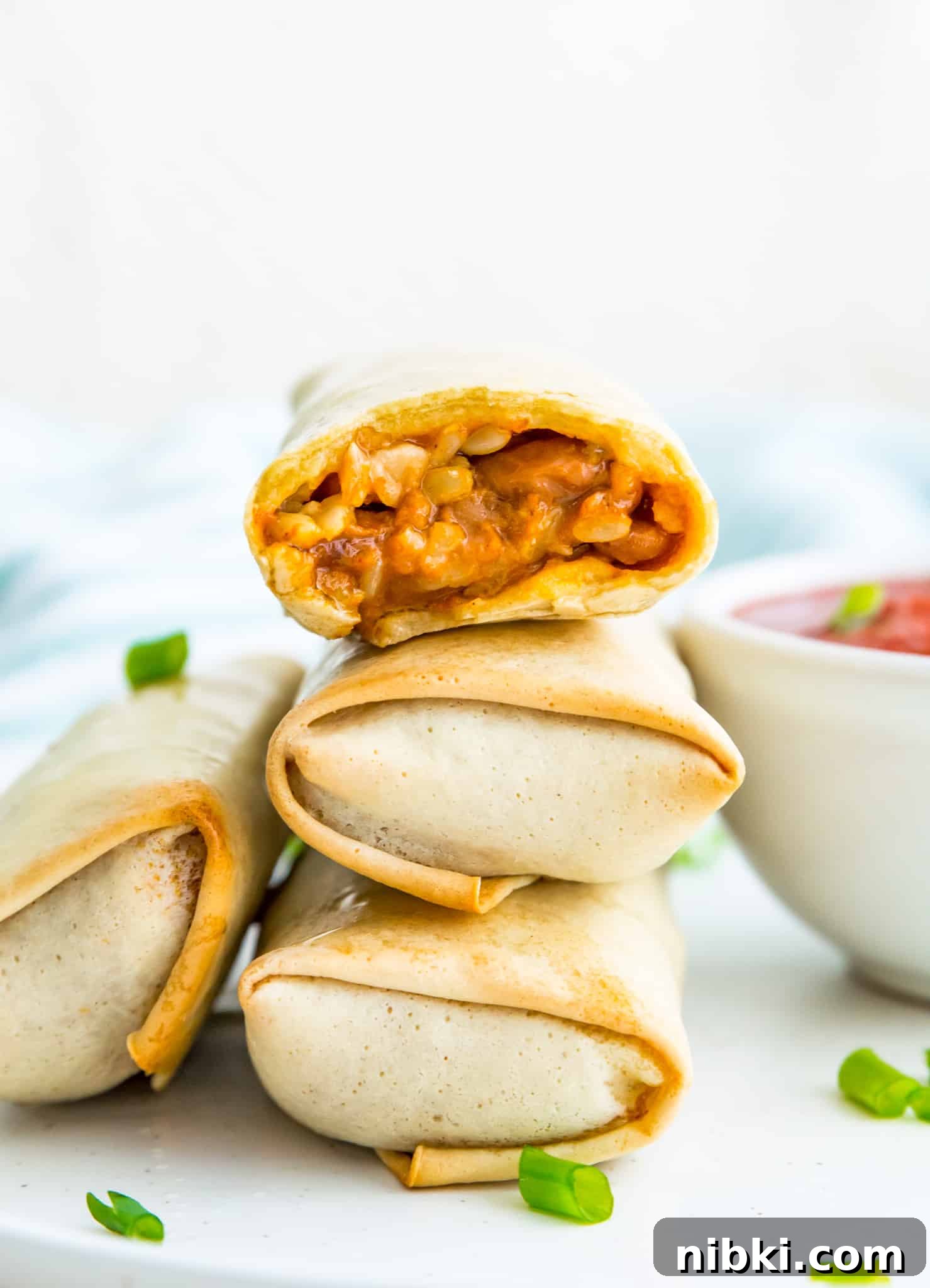 stacked air fryer burritos A stack of cooked burritos and the top one has a bite out of it.