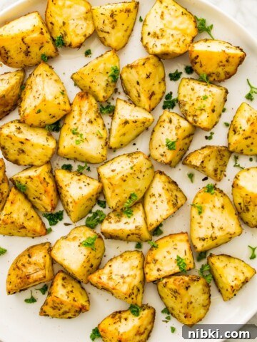 A plate of cooked, diced potatoes garnished with fresh parsley.
