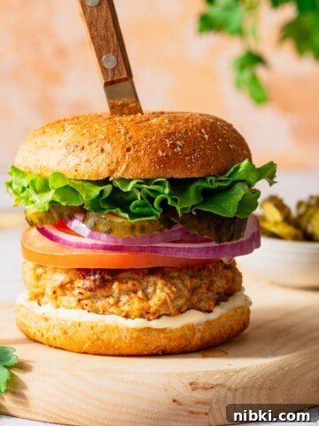 A turkey burger in a bun topped with lettuce, tomato, onion and pickles.