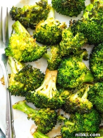 A plate of cooked broccoli with a fork beside it.