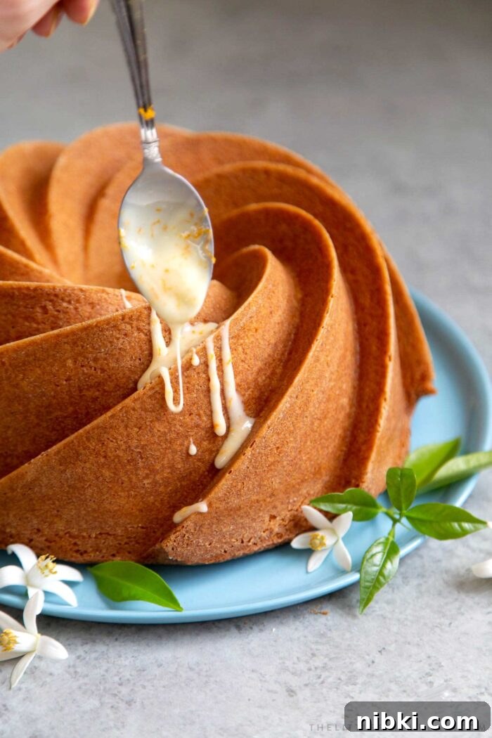 Fragrant Orange Blossom Bundt Cake with Citrus Glaze 10 Orange blossom bundt cake drizzled with orange glaze on blue serving plate.