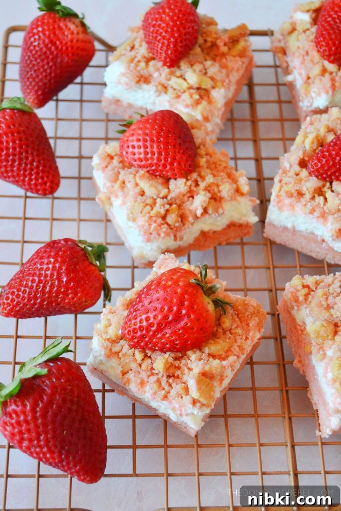 a wire rack with strawberry shortcake bars arranged all over it and fresh berries on the side