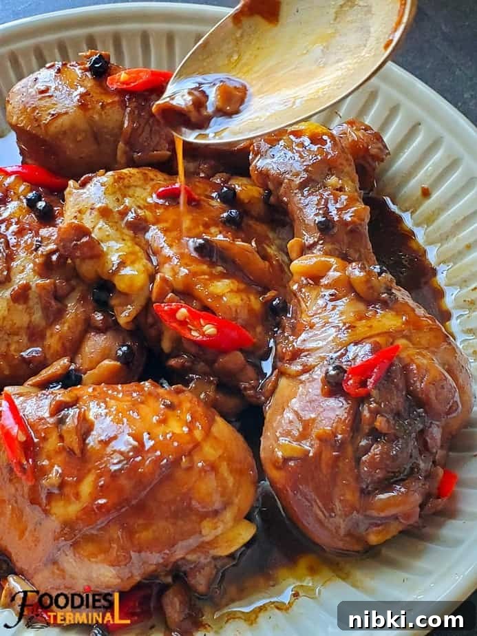 filipino chicken adobo instant pot served in beige bowl sauce being drizzled with spoon