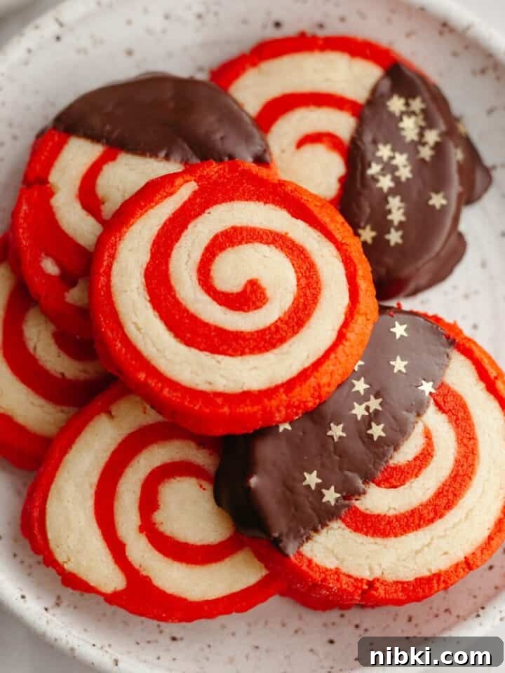 Red and white pinwheel candy cane shortbread cookies on a small plate.