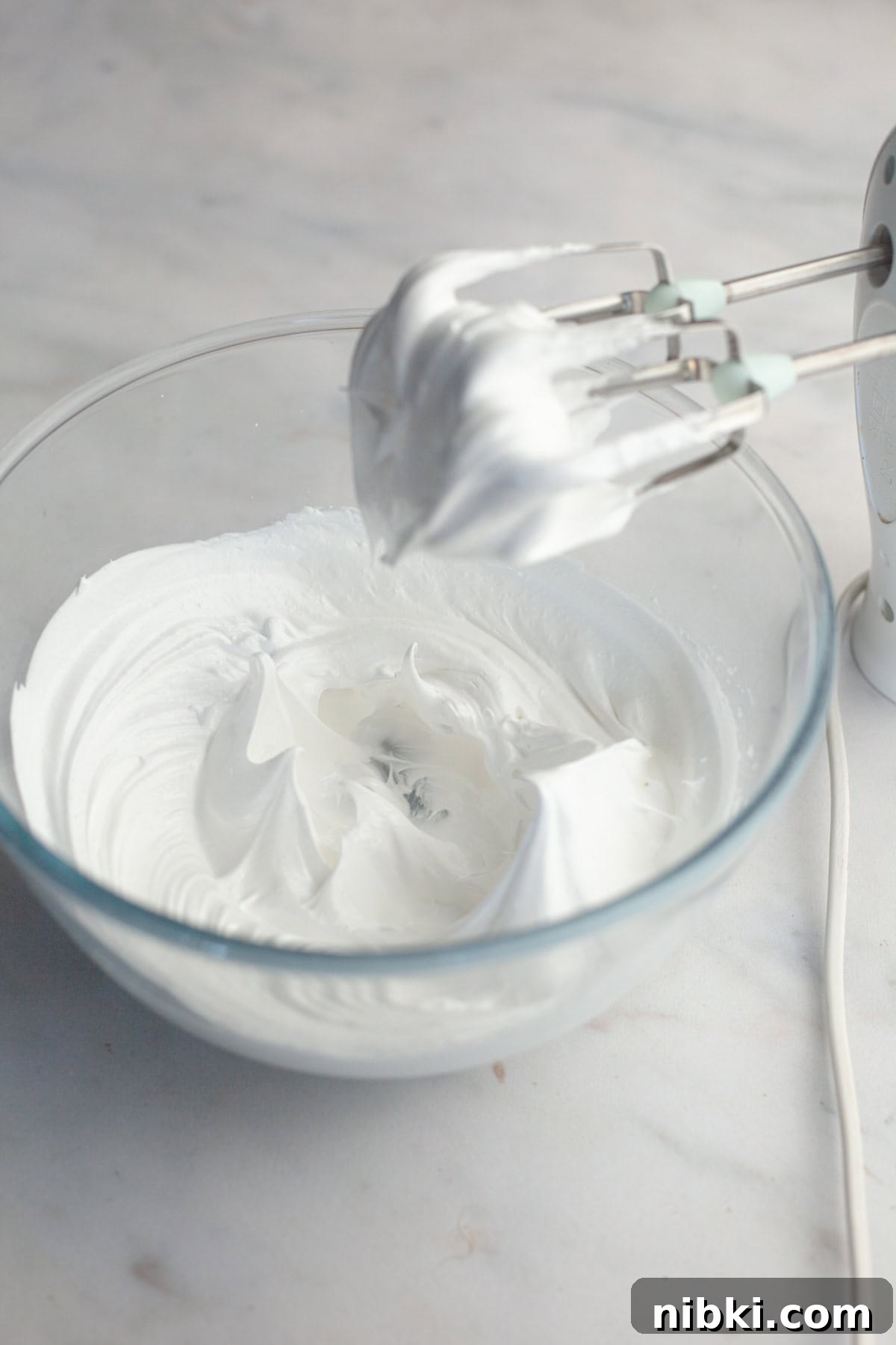 A glass bowl with stiff glossy meringue peaks.