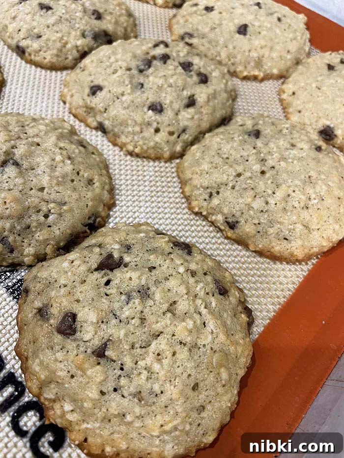 A closeup photo of banana oatmeal cookies on a baking sheet lined with a silicone baking mat.
