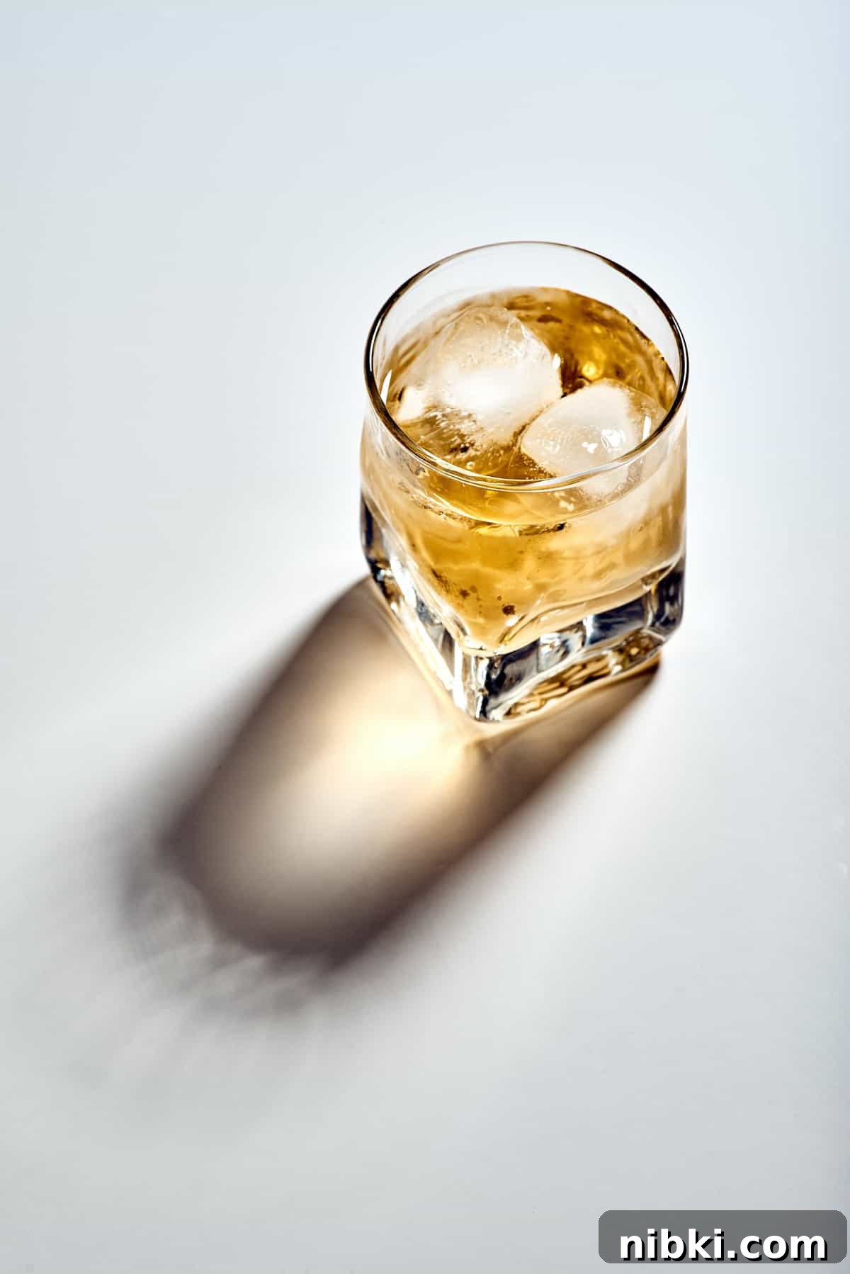 A glass of liquor on the rocks on a white background.