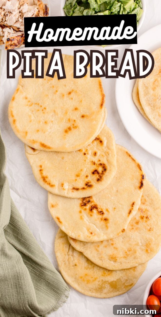 Five pieces of homemade pita bread are stacked on parchment paper, surrounded by fresh salads and flavorful toppings.