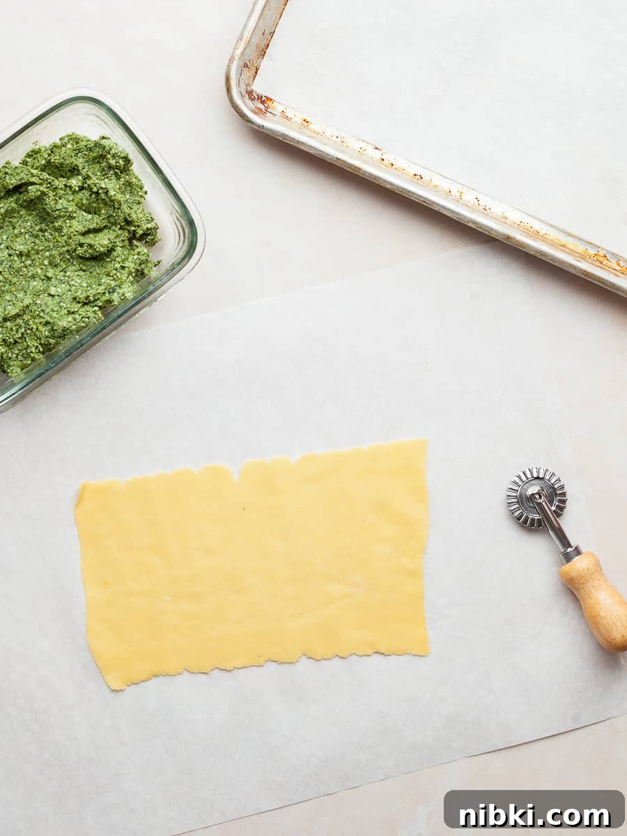 Homemade Gluten-Free Spinach and Ricotta Ravioli 13 a sheet of gluten free pasta, a container with spinach ricotta ravioli filling and a pastry cutter on a table