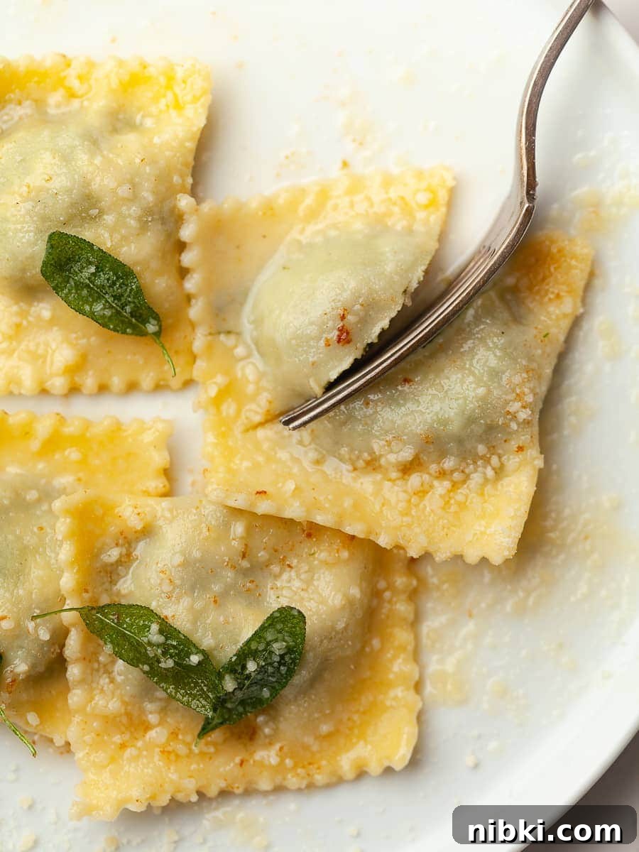 Homemade Gluten-Free Spinach and Ricotta Ravioli 4 gluten free spinach ricotta ravioli on a white plate with brown butter, parmesan cheese and crispy sage, a fork in the corner that's splitting one ravioli in half