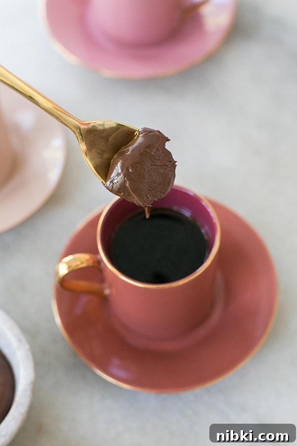 Homemade Chocolate Hazelnut Coffee Recipe 3 spoon with chocolate hazelnut on a gold spoon going into a cup of hazelnut coffee.