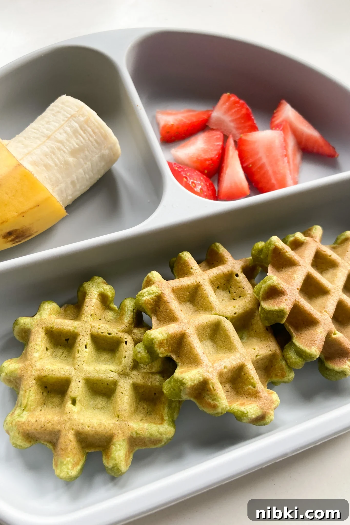 Fluffy Spinach and Banana Waffles Recipe 5 Spinach banana waffles served with a banana and strawberries