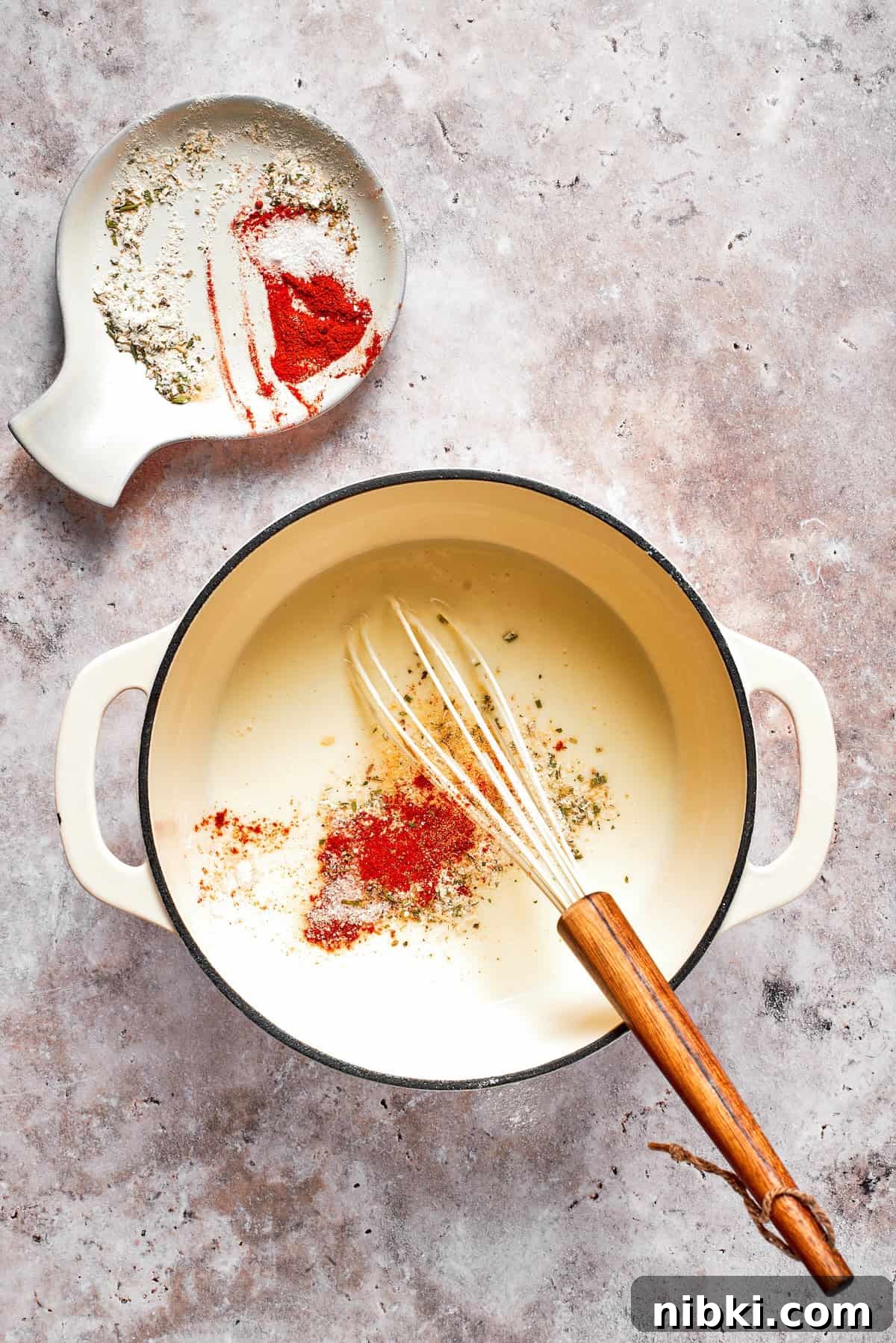 Spices are whisked into a pot of sauce.