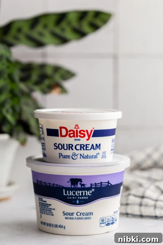 2 tubs of sour cream stacked on top of each other with a plant in the background