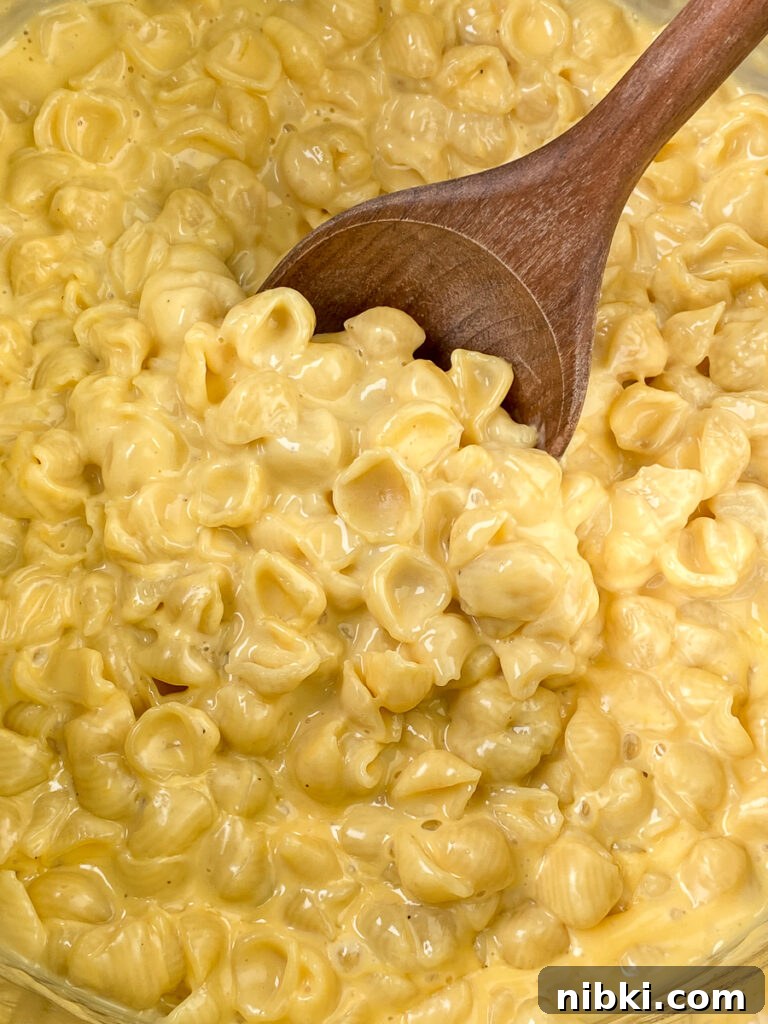 Creamy Instant Pot Mac and Cheese with Velveeta 3 Wooden spoon in pot full of creamy and cheesy mac and cheese