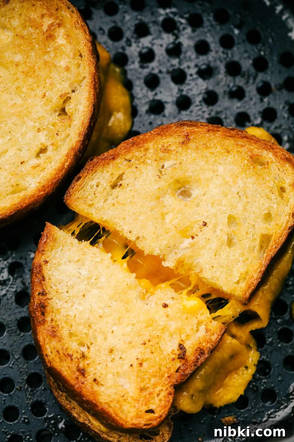 Fourth photo of grilled cheese cut in half in the air fryer basket.