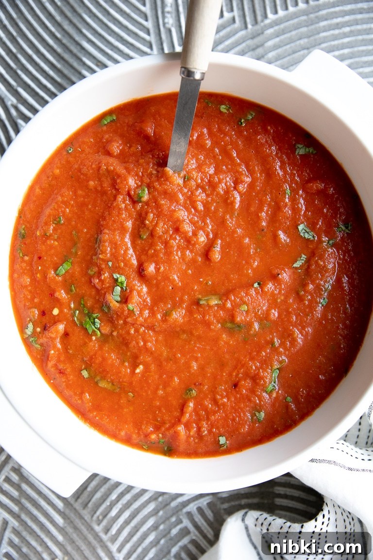 Image of a large white Dutch oven filled with blended homemade Tomato Basil Soup.