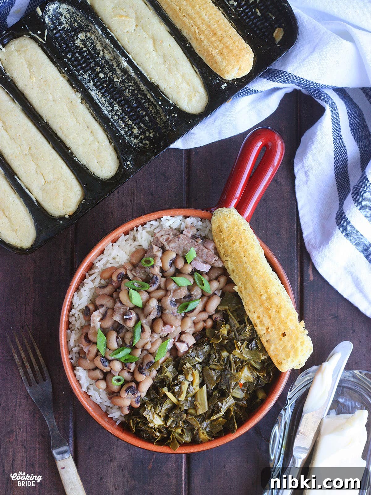 Instant Pot Hoppin' John: Southern Black-Eyed Peas and Rice 2 Overhead shot of a red bowl with a handle filled with rice, Hoppin' John and greens. A pan of cornbread and a dish of butter with a knife are to the side.
