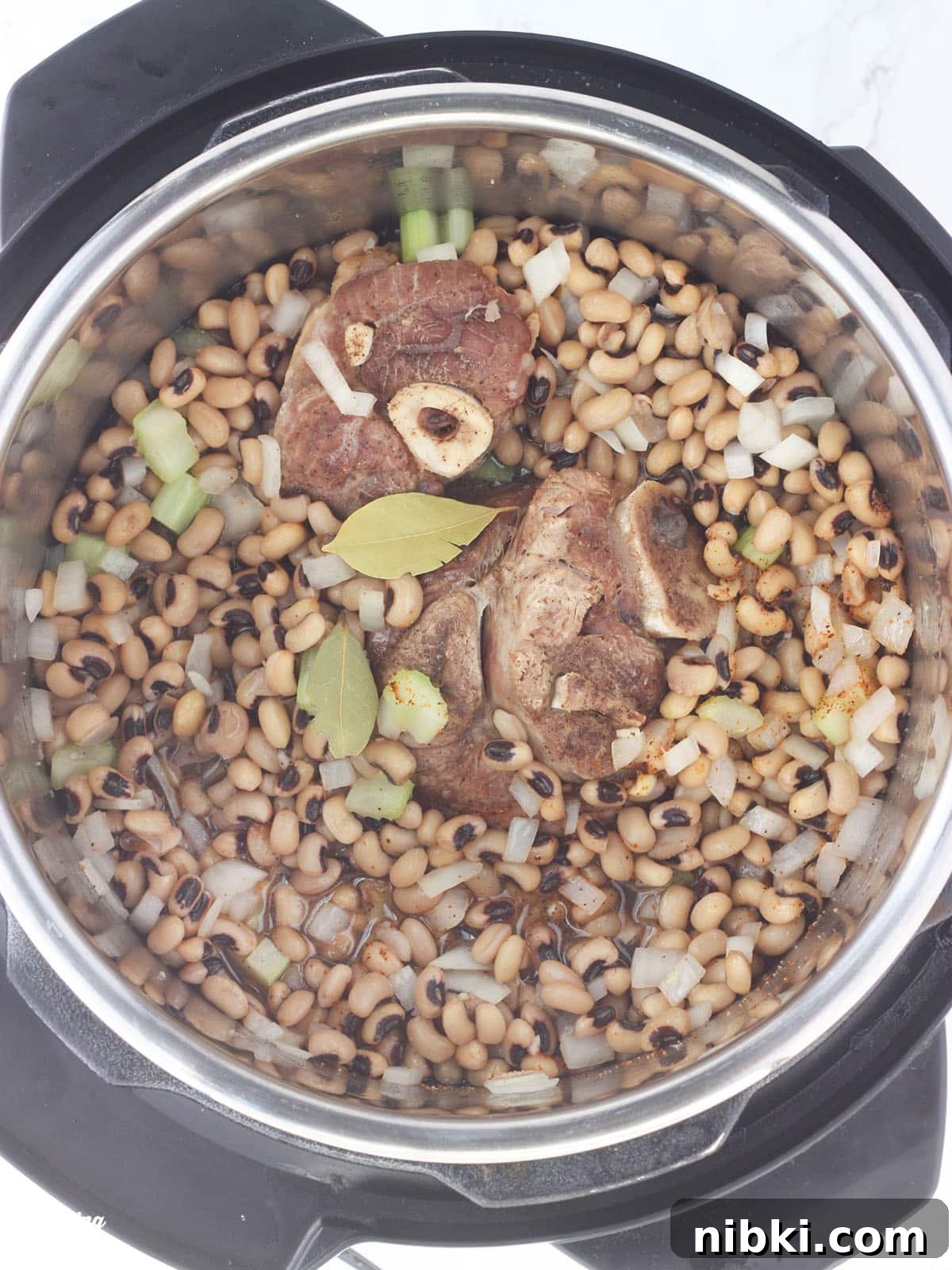 Instant Pot Hoppin' John: Southern Black-Eyed Peas and Rice 6 overhead shot of black-eyed peas, ham hock and bay leaves in an Instant Pot