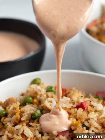Homemade Lemon Garlic Aioli Recipe 7 A bowl of fried rice with yum yum sauce being poured on top.