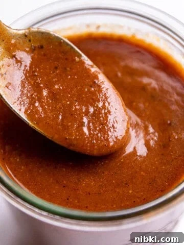 Homemade Lemon Garlic Aioli Recipe 8 A spoon scooping enchilada sauce out of a glass jar.