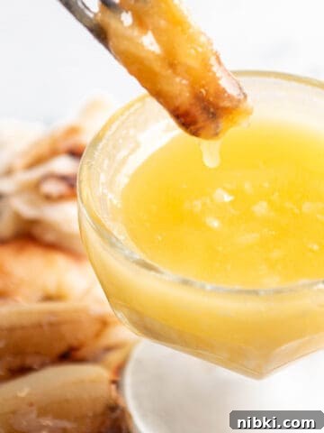 Homemade Lemon Garlic Aioli Recipe 9 A piece of crab meat being dunked into a bowl of butter.