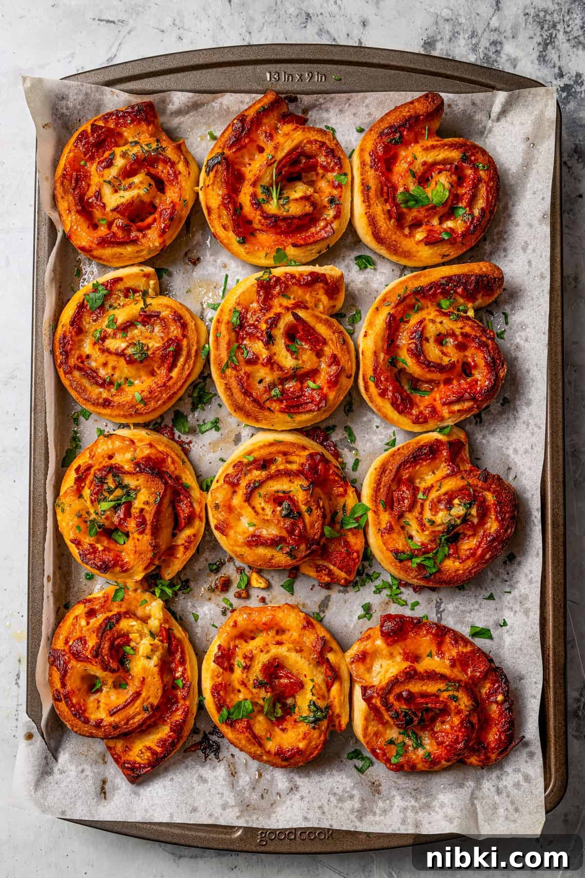 Cheesy pizza rolls are the easiest and best appetizer, made with flaky dough, tangy tomato sauce, melty mozzarella, and pepperoni. Rows of pepperoni pizza rolls arranged on a parchment-lined baking sheet.