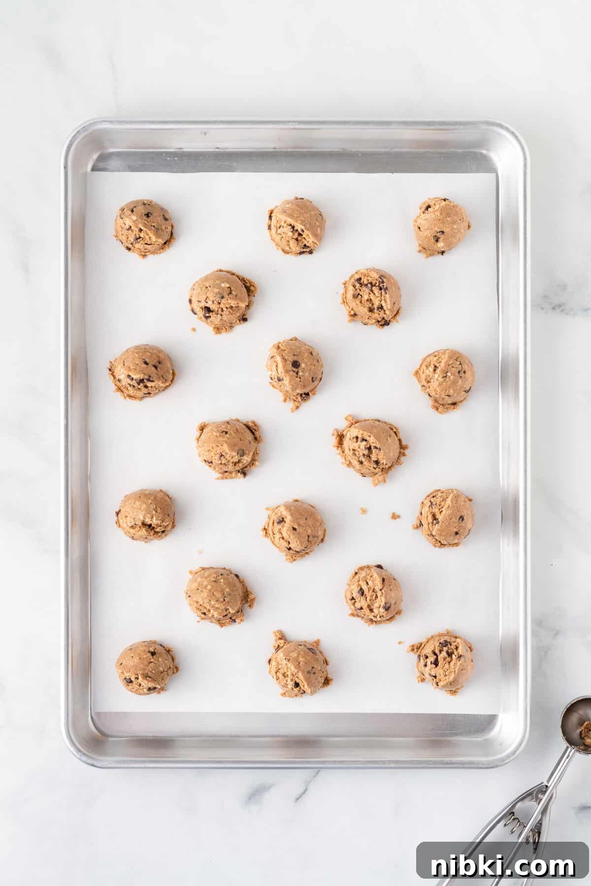 scoops of energy ball batter on a lined baking sheet