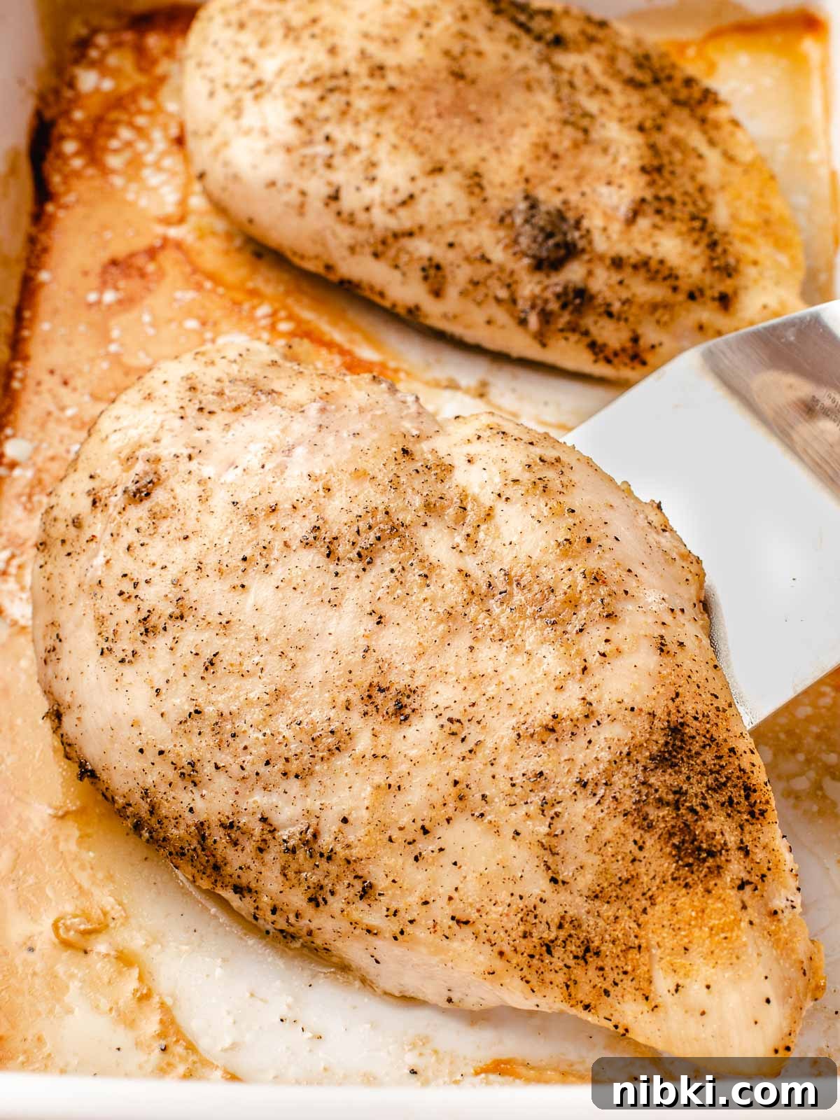 Tender Oven-Baked Chicken Breasts with Garlic and Herbs 2 Baked chicken breast in a baking dish.